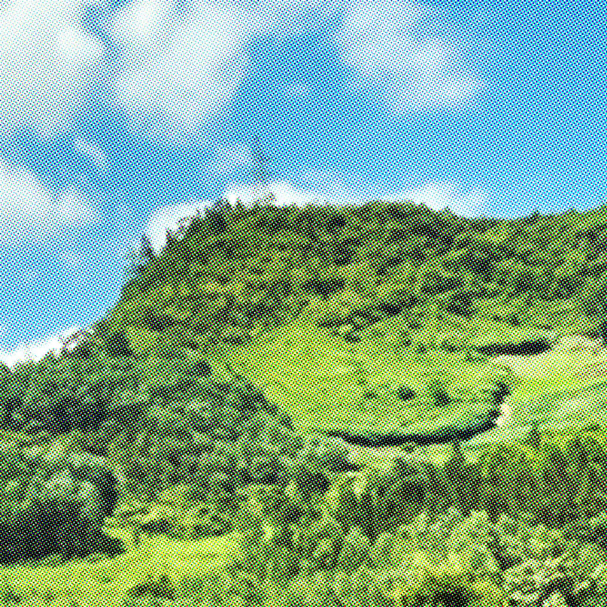 A black-and-white photo of a hill, in which the surface resembles two eyes and a mouth on a face.
